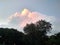 a giant yellowish pink cloud floating in the sky