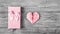 A gift box with a bow and a delicate pink heart made of paper on a gray background. Postcard heart of origami. Copy space