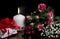Gift box, burning candle, red and white flowers, berries, greeting card for lovers on black background. Love and passion