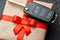 Gift box with car keys with remote control alarm system with red ribbon bow.