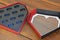 Gift box. Empty heart-shaped paper box in black plastic with aged wooden base, red and black box, Brazil, South America, top-down