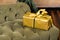 gift box with gold and green ribbons lying on classic velvet green sofa at home. christmas, x-mas, holidays, winter and