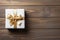 Gift box with golden ribbon and bow on the wooden table top. Holiday gift with Birthday or Christmas present, top view.