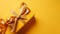 Gift box with golden satin ribbon and bow on yellow background. Holiday gift with copy space. Birthday or Christmas present, flat