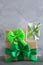 Gift box with green bow on grey concrete background