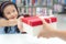 Gift box for kids girl. White box with red bow in the smiling asian girl hands for give a gift in the library.
