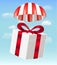 Gift box with parachute on sky background