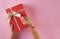 Gift box on an  pink background. Rectangular gift box. Woman`s hands grabbed the box