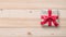 Gift box present isolated with clipping path with red bow satin ribbon over brown wrapping paper on white pine wood background f