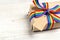 Gift box with rainbow LGBT ribbon and empty tag for inscription on a light wooden background.