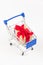 Gift box with a red bow and ribbon in a metal shiny shopping trolley on wheels on a white background