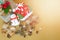 Gift box with red flower, snowman, santa claus house, pine cones, dry leaves and star decoration on golden background