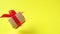 Gift box with red ribbon spinning on yellow background. 360 degree rotation. zero gravity. levitation. copyspace. Concept sales, d