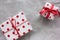 Gift box in red and white wrapping paper with hearts and ribbons on gray background. View from overhead.