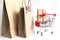 Gift box on shopping cart and shopping bags on white background