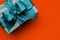 Gift box with turquoise ribbon on orange background
