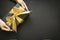 Gift box wrapped in black paper with gold ribbon in female hand on black surface.