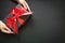 Gift box wrapped in black paper with red ribbon in female hand on black surface.