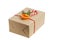 Gift box wrapped in kraft paper, tied with red twine and decorated with a juniper branch, orange slice and candy cane.