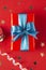 Gift box wrapped in re paper with blue ribbon on red surface. Christmas, party, birthday concept
