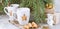 gift boxes,mug with drink decorated with marshmallow and star shape cookies near evergreen christmas tree branches concrete