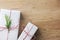 Gift boxes wrapped in white paper tied with striped red ribbon twig of green juniper on brown wood background. Christmas New Years