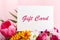 Gift card in flowers bouquet on pink background. Gift card present coupon for woman. Surprise voucher for Mother`s Day, Happy