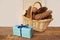 Gift in a cardboard box tied with a blue satin ribbon, beautiful pine cones in a wicker basket on a light festive background with