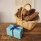 Gift in a cardboard box tied with a blue satin ribbon, beautiful pine cones in a wicker basket on a light festive background with