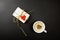 Gift and a cup of cappuccino on a black background. Retro gift is decorated with a heart, in the center of the coffee drink is a