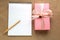 A gift in a pink box decorated with silk ribbon, a blank sheet o