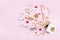 Gift or present box with confetti stars, golden ribbon and holiday decoration on pastel pink background. Christmas flat lay.