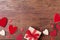 Gift or present box and red mixed hearts on rustic table top view. Valentines day greeting card.