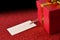 Gift with tag on bright red textured table elevated view