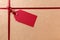 Gift tag and red ribbon, brown parcel wrapping paper background, copy space