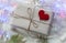 Gift tied with string with a red heart on a knitted white sweater, garland, branches of thuja-the concept of making gifts for the