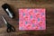 Gift wrapped with pink birthday paper, tape dispenser and scissors, wood table