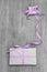Giftboxes with purple striped ribbon on a grey wooden backround