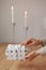 gifts in white packaging are on the table against the background of candles. a woman& x27;s hand holds a packed gift for the