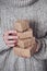 Gifts in women`s hands, close-up. Monochrome, minimalist gift concept. A girl in a sweater holds gift boxes made of Kraft paper,