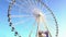 Gigantic observation wheel rotating against cloudless blue sky, entertainment