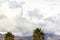 Gigantic thick white and gray clouds, with san gabriel mountains and palm trees