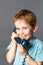 Giggling little boy talking on a blue old fashioned telephone