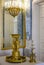 Gilded antique vases decorated with bas-reliefs with mythical subjects, against the background of mirrors and chandelier