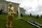 Gilded statue of Capitoline Antinous against grassy slope with fountain and Big Peterhof Palace in Saint-Petersburg, Russia