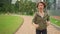 gimbal shot tracking young attractive and fit woman in hoodie running at green city park in morning jogging