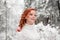 Ginger beautiful female in white sweater in winter forest. Snow december in park. Portrait. Christmas cute time.