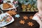 Ginger biscuits in the form are painted with glaze, aysing. Christmas tree branches on a white wooden texture background. The conc