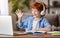 Ginger boy in headphones greeting teacher during online lesson