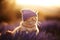 Ginger cat in purple knitted hat in sunset, lavender field. Generative AI